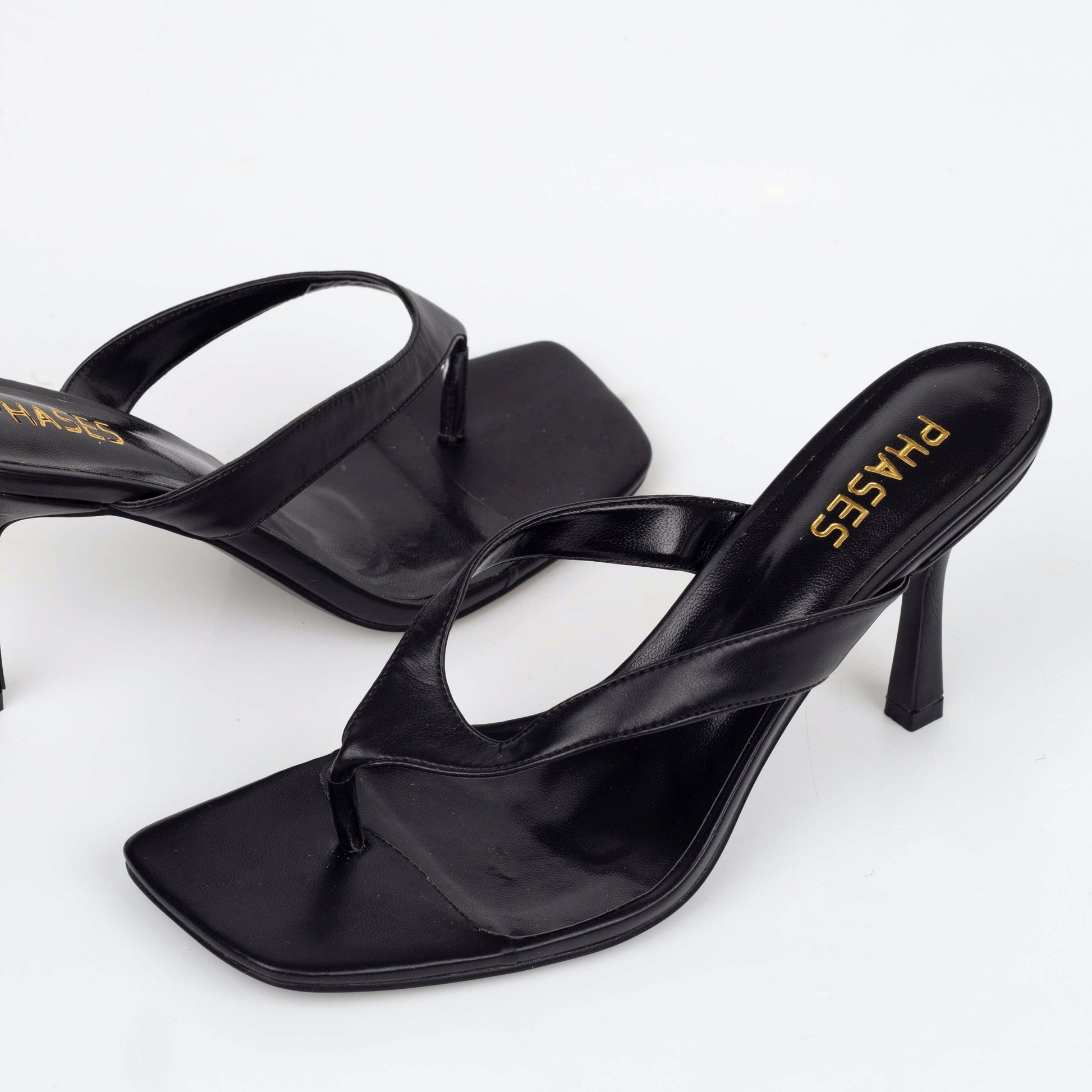 Close up of black flip-flop heels with gold logo